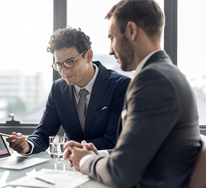 Two guys sitting in a board room pointing at a screenshot
